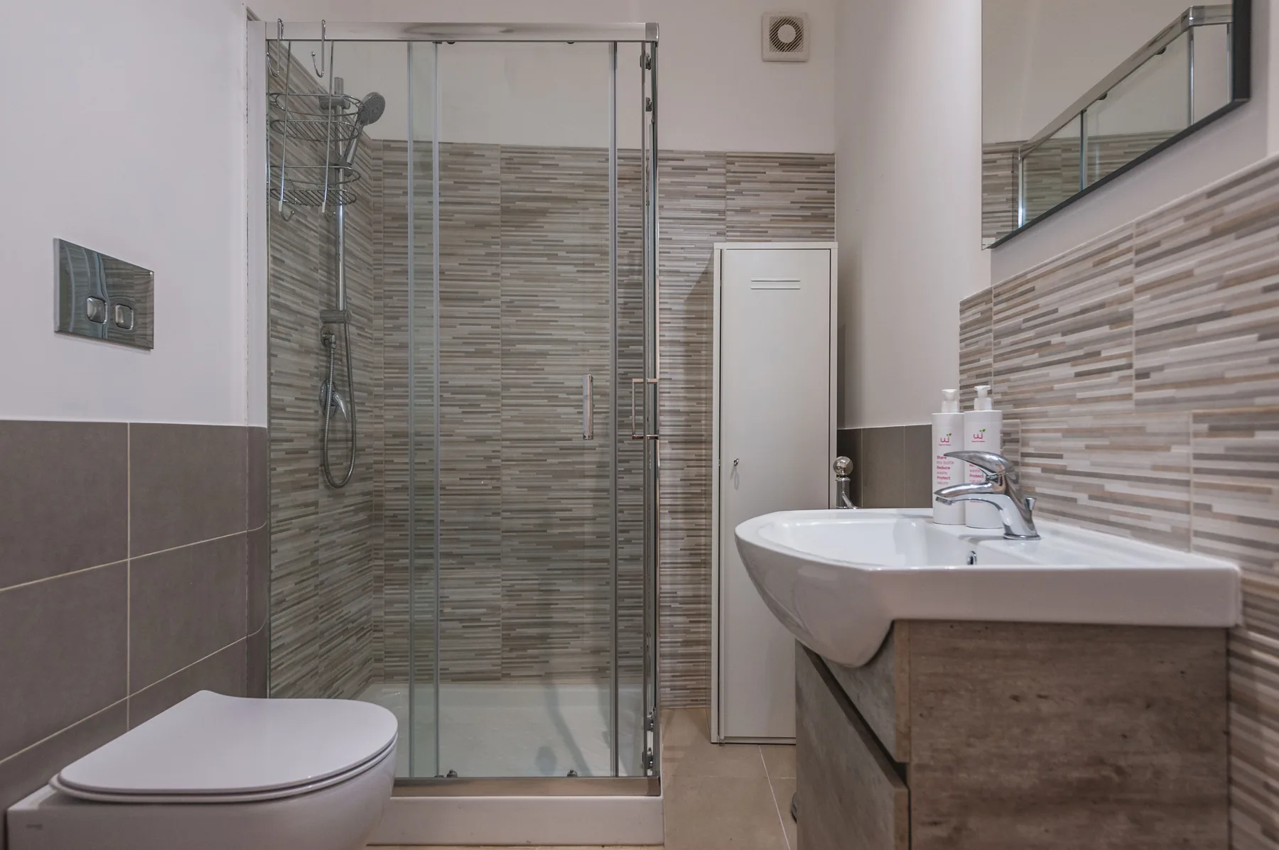 Un baño con ducha de vidrio, lavabo e inodoro.