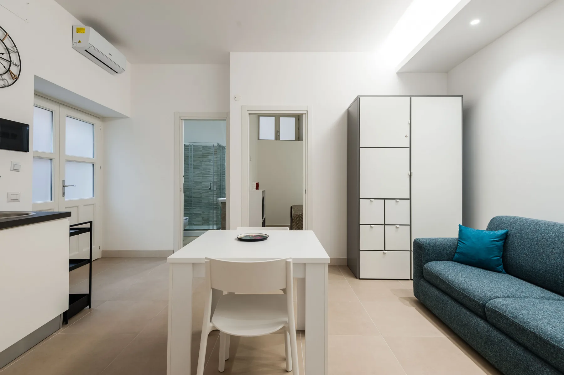 Una luminosa sala de estar y comedor con una mesa blanca y asientos azules.