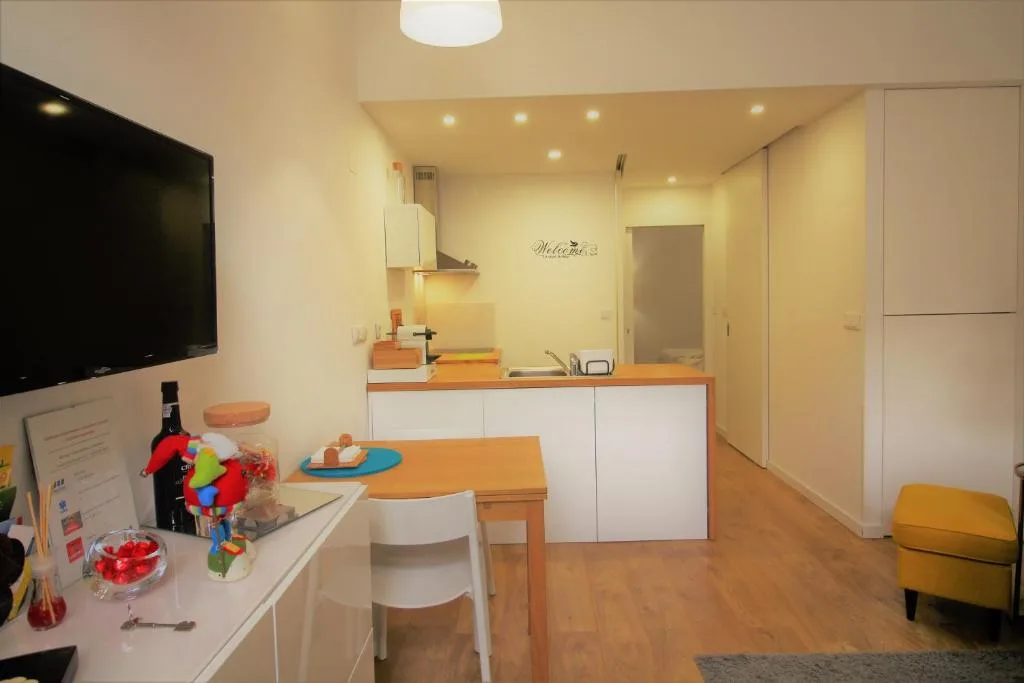 A compact dining and kitchenette area with a table, counter, and wall-mounted television.