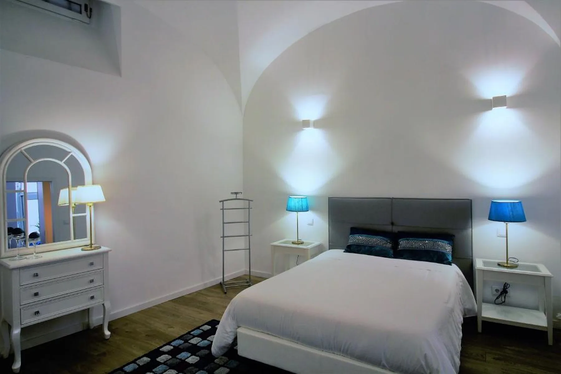 A bedroom with a bed beneath a curved white ceiling and bedside tables.