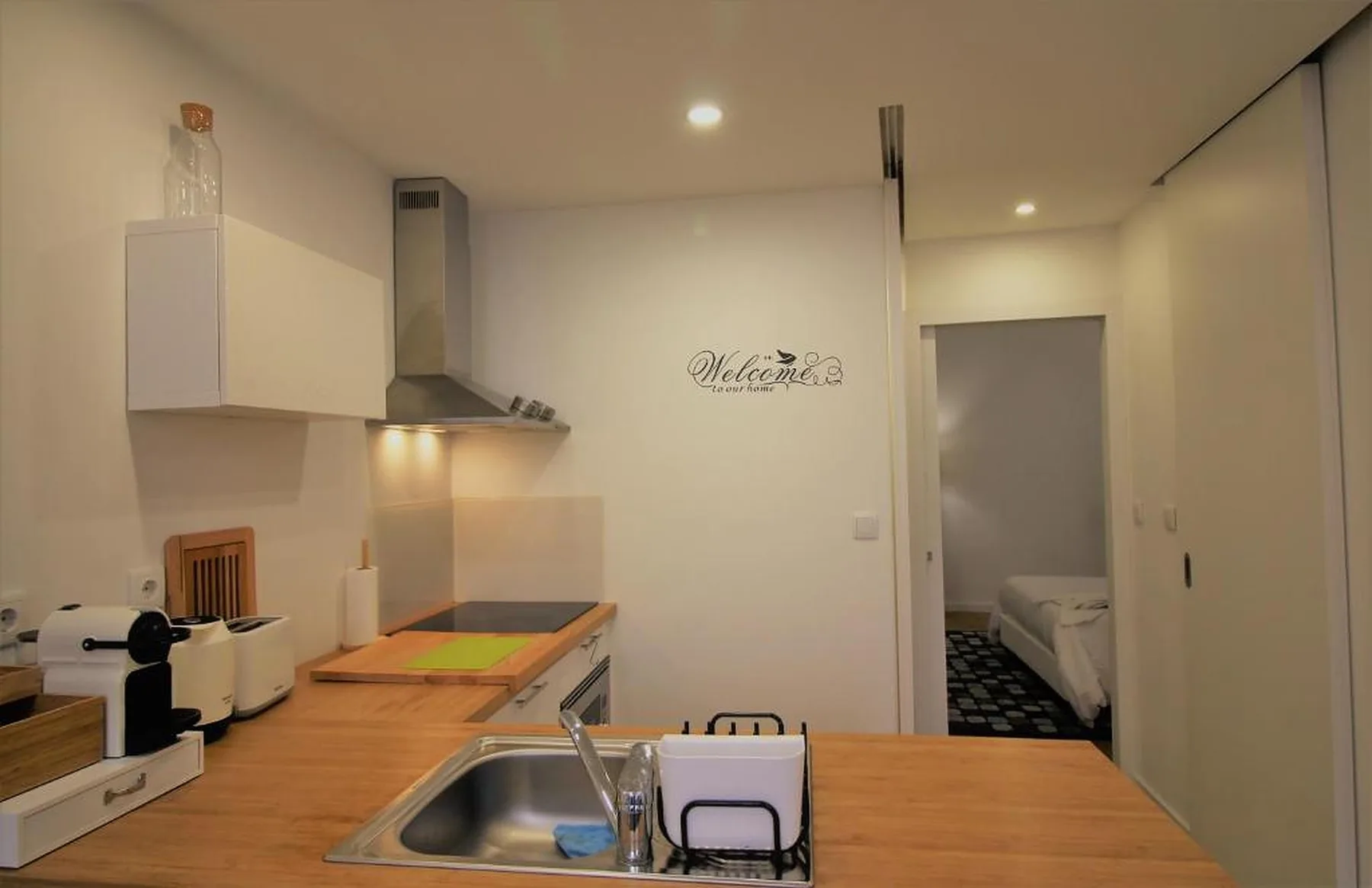 A compact kitchen with wooden counters and a sink opens onto a sleeping area.