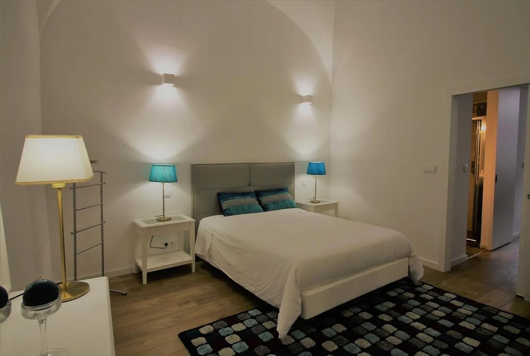 A bedroom with a bed, bedside tables, and lamps.