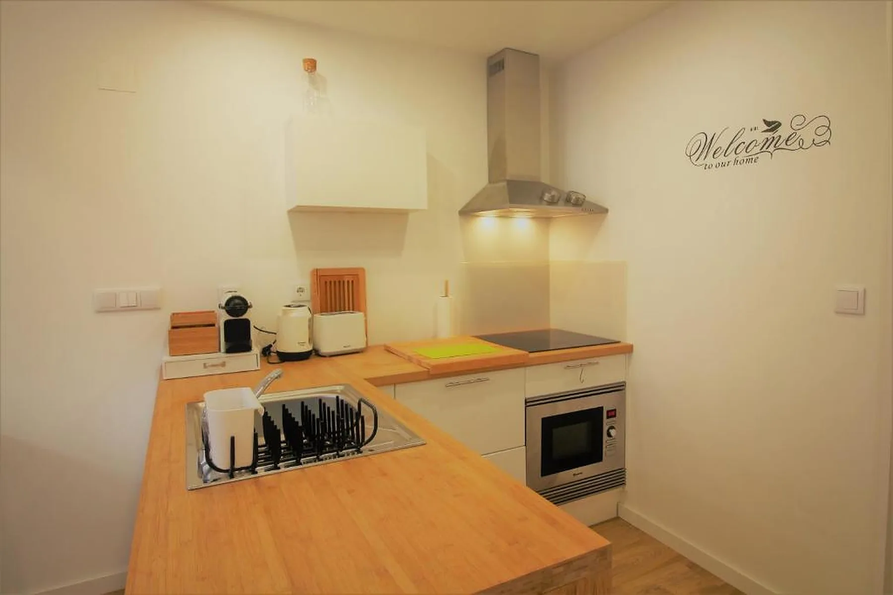 A compact kitchen with wooden countertops, a cooktop, and an oven.