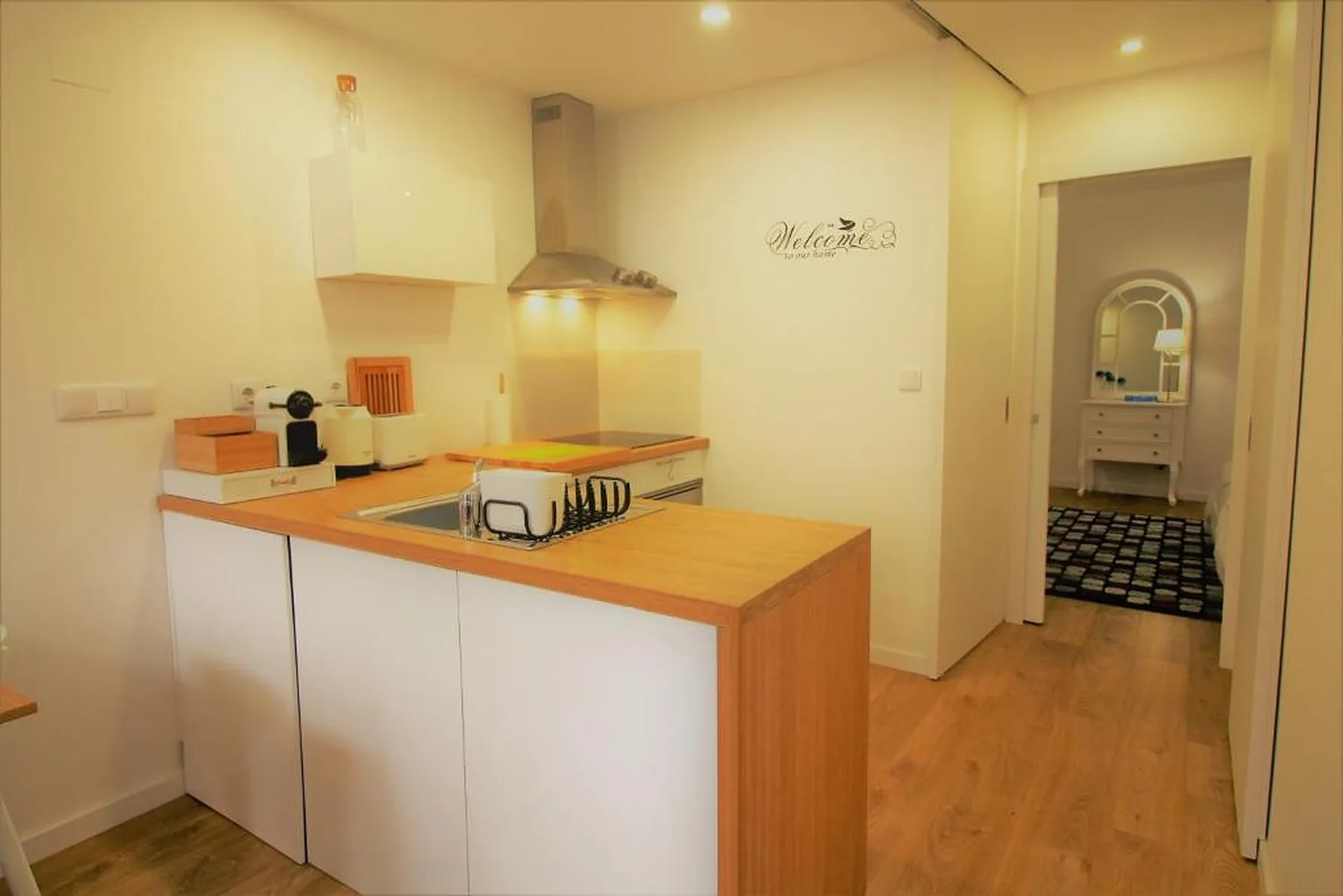 A bright kitchen with a wooden counter and an open doorway to another room.