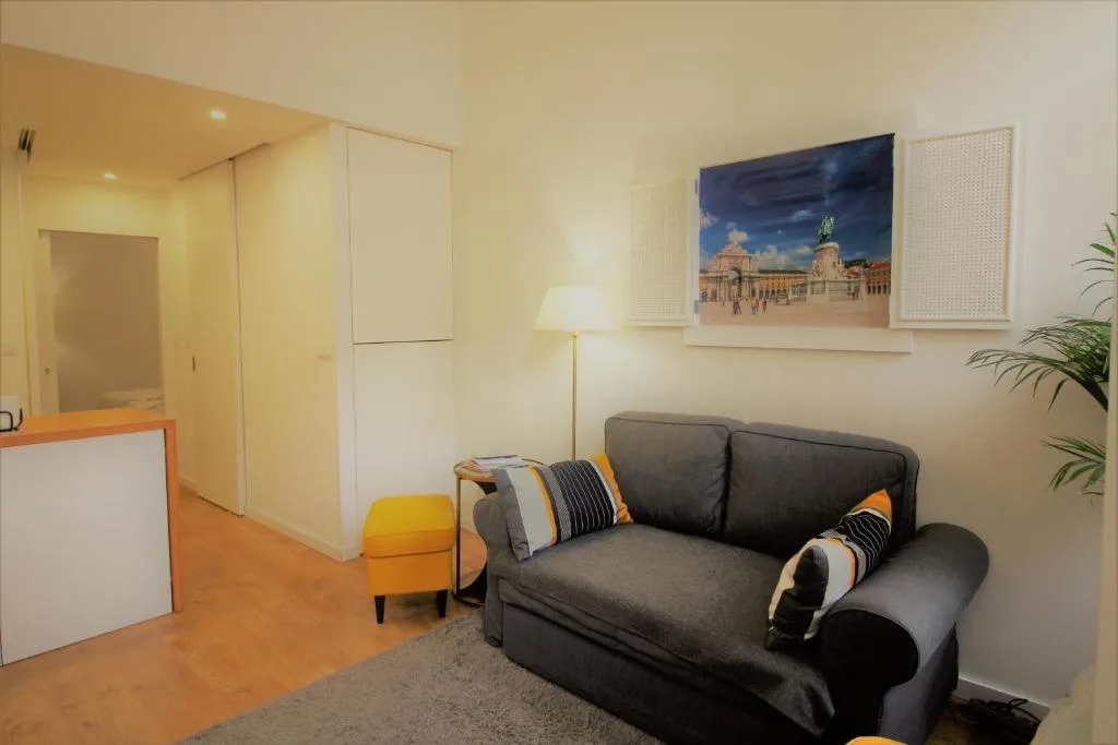 Sala de estar con asientos oscuros, una lámpara de pie y arte enmarcado en la pared.