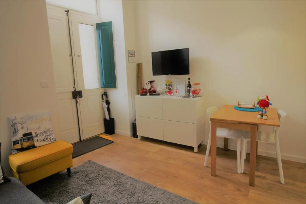 Una sala de estar con televisión, un mueble y una pequeña mesa de comedor.