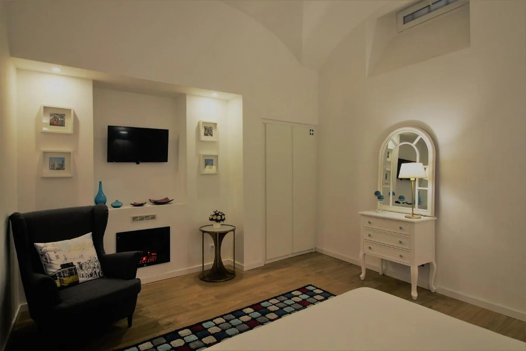 A living room with seating, a television, and a dresser with a mirror.