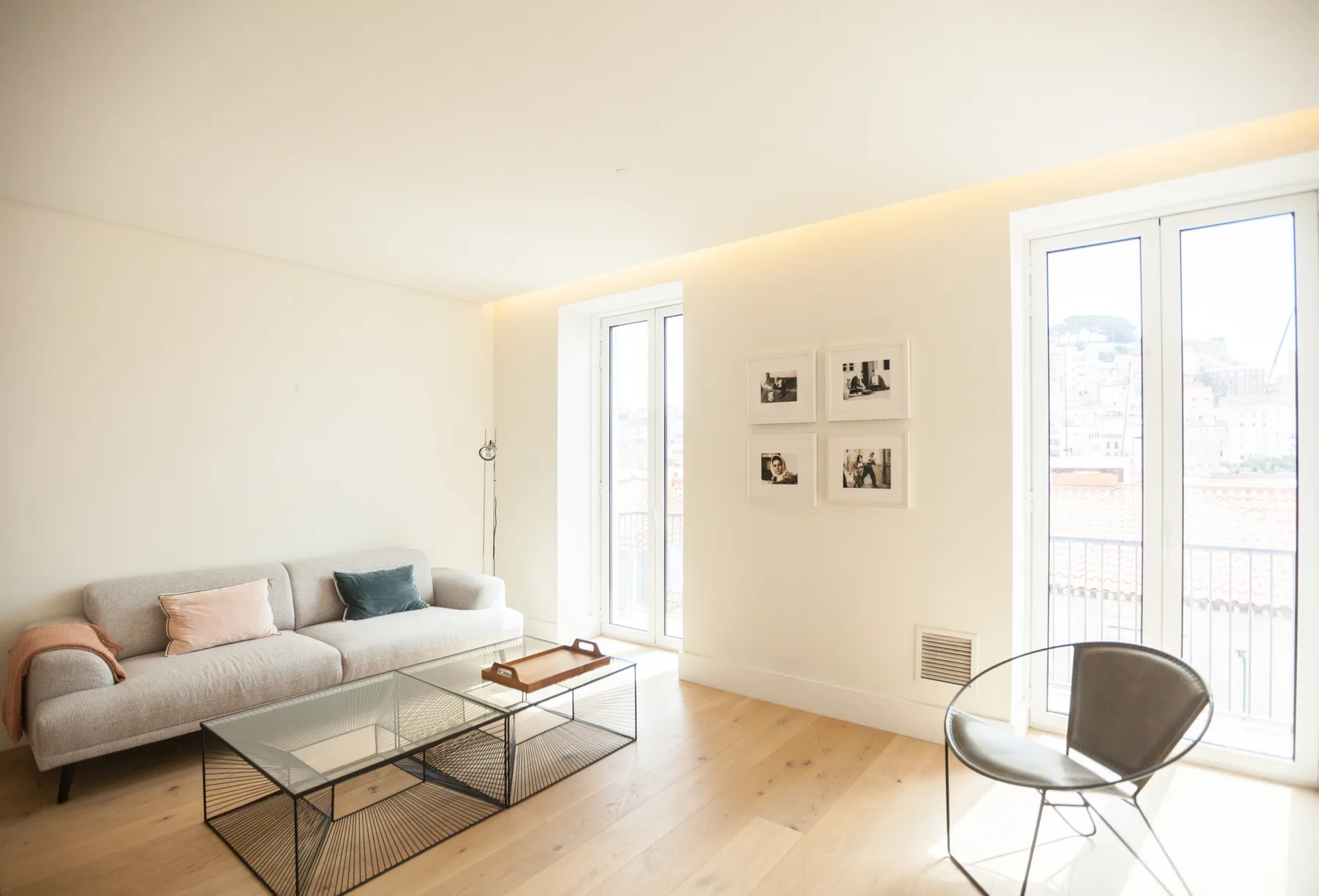 Una sala de estar luminosa con asientos, una mesa de centro de vidrio y ventanas altas.
