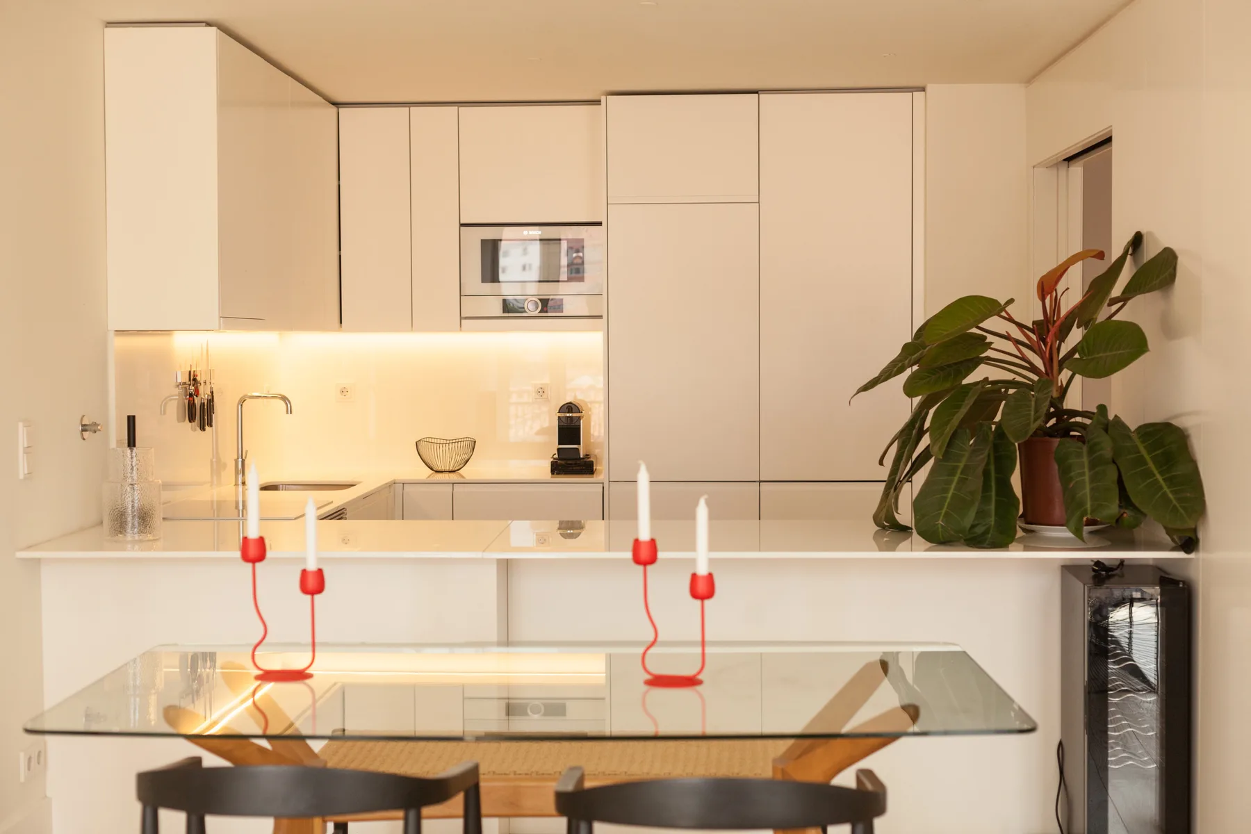 Una cocina moderna con gabinetes blancos, una encimera y una planta.