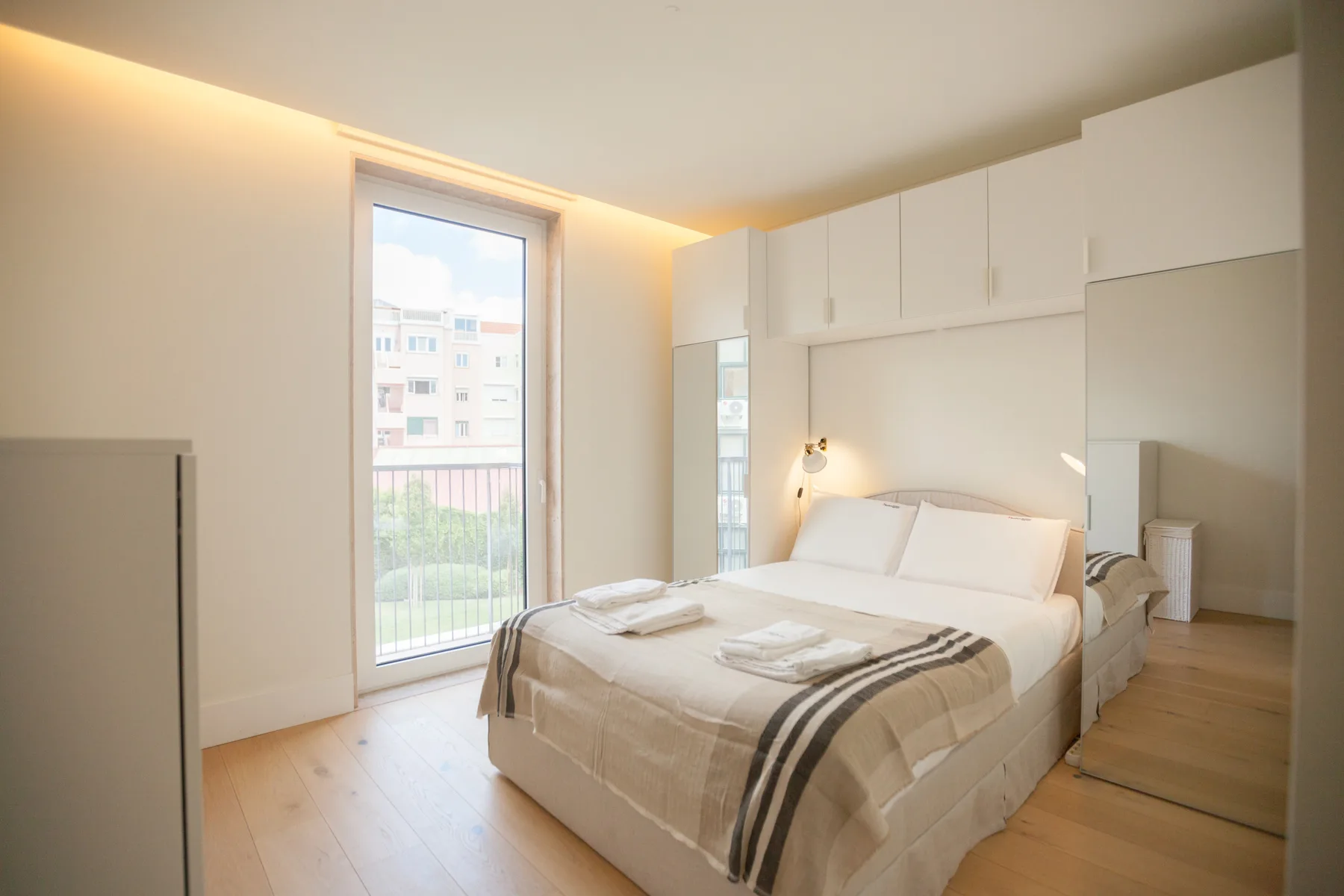 Un dormitorio luminoso con una cama doble y armarios blancos empotrados.