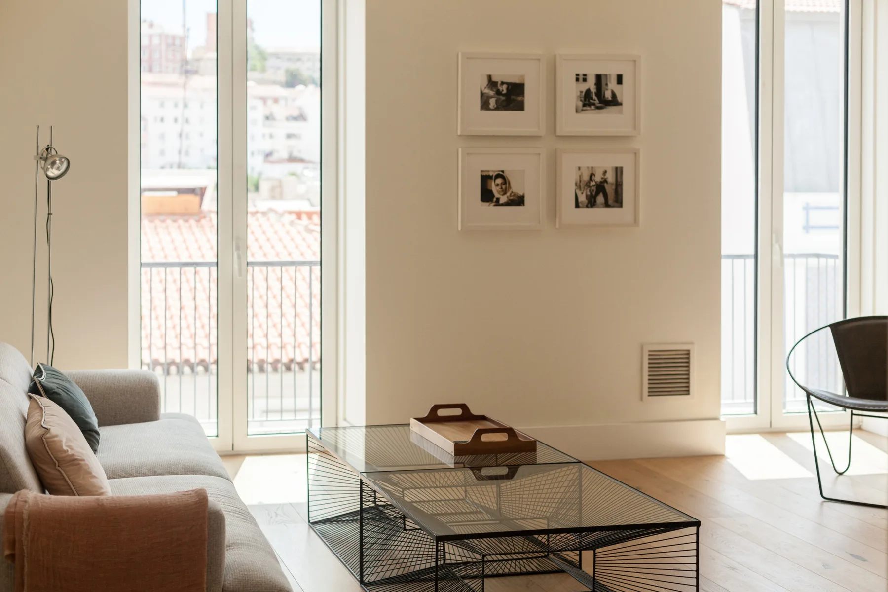 Una sala de estar luminosa con asientos, una mesa de centro de vidrio y ventanas altas.