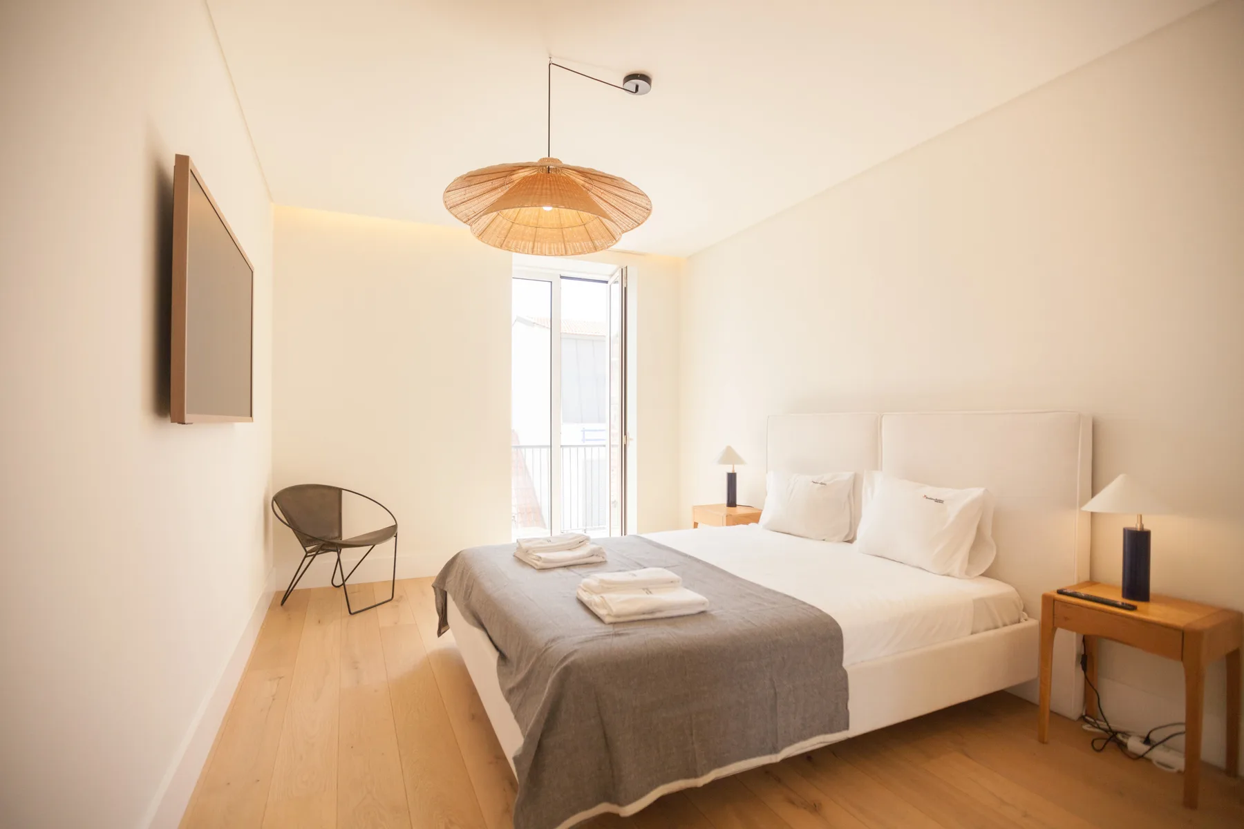 Un dormitorio luminoso con una cama y una ventana alta.