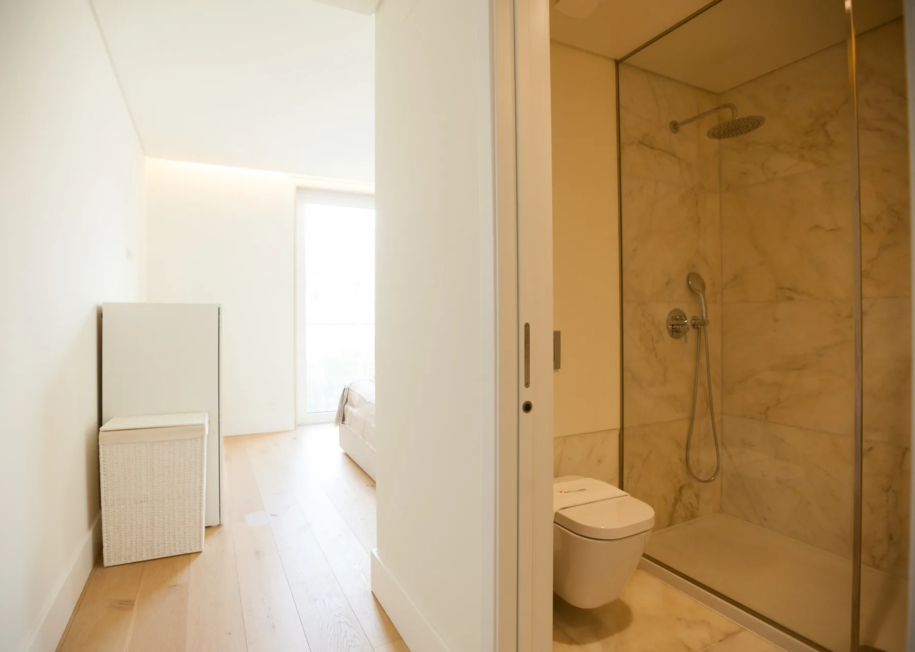 Se ve una zona de dormitorio luminosa junto a un baño con ducha.