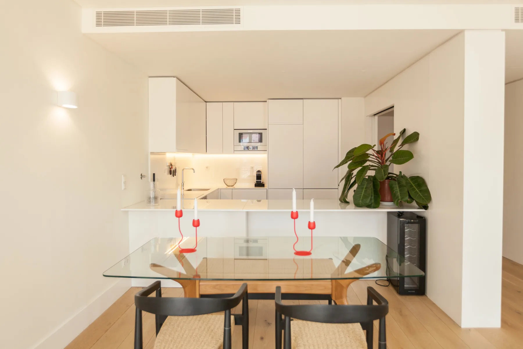 Comedor con una mesa de cristal y una cocina abierta al fondo.