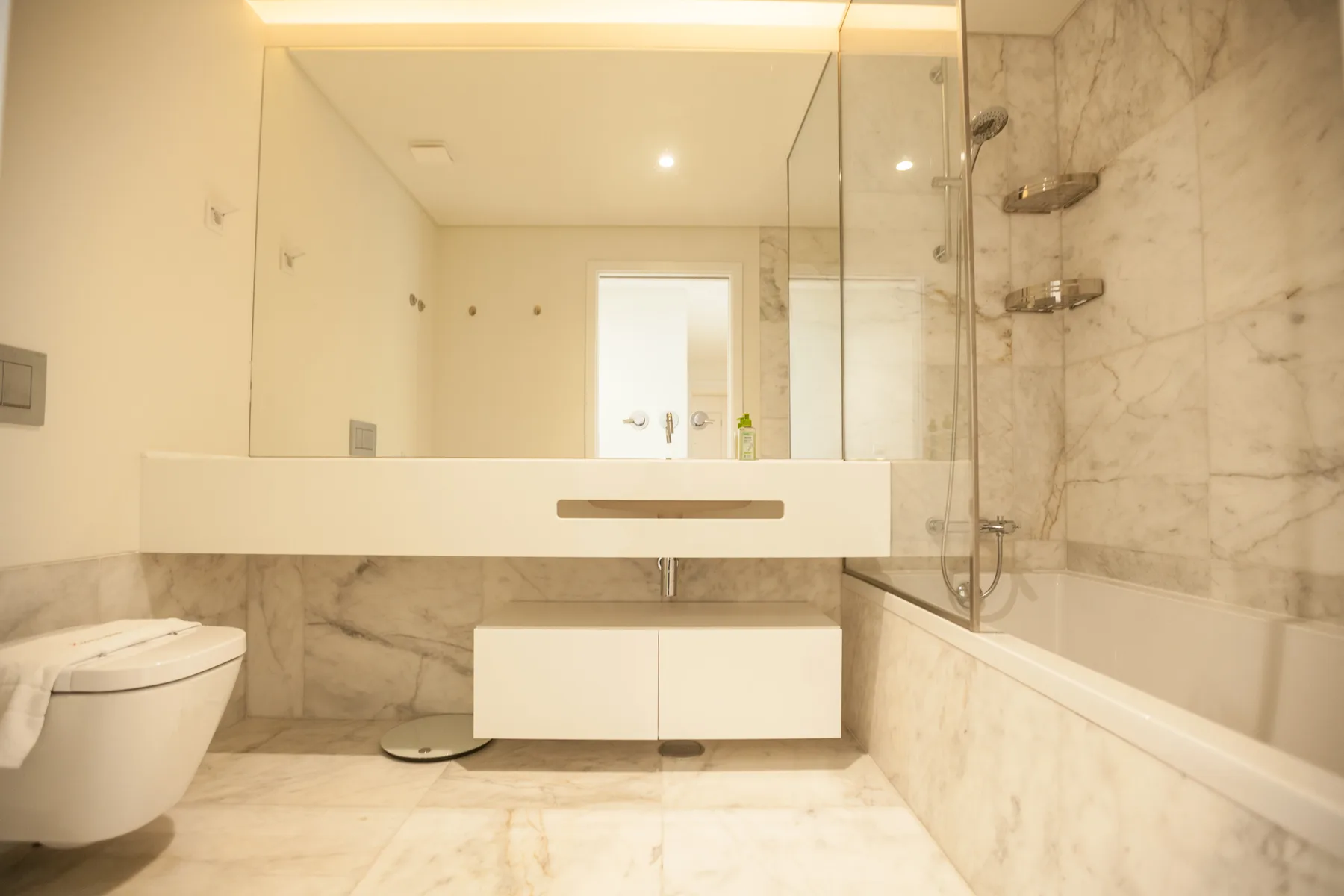 Un baño luminoso con una amplia encimera de lavabo, espejo de pared y bañera.