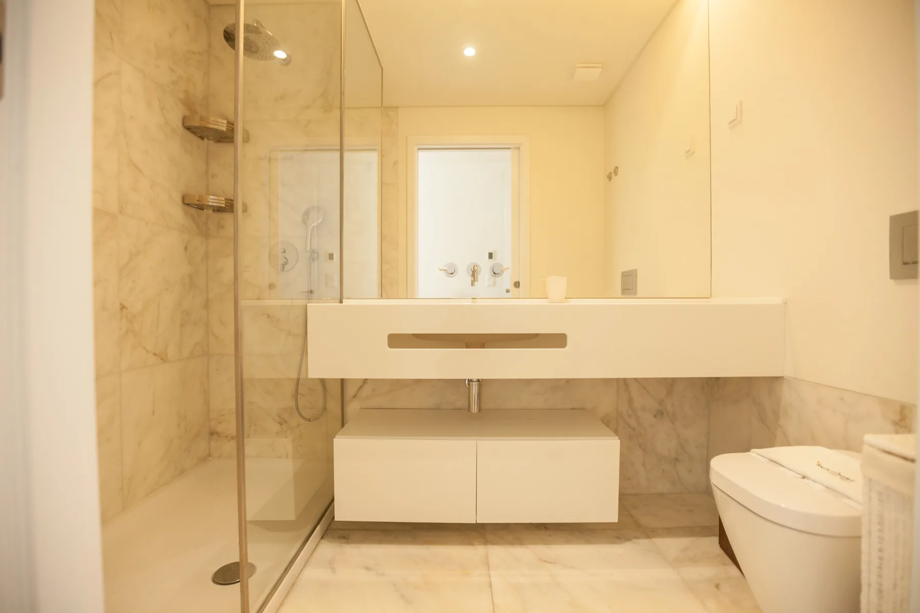 Un baño luminoso con un lavabo amplio, espejo y ducha de vidrio.
