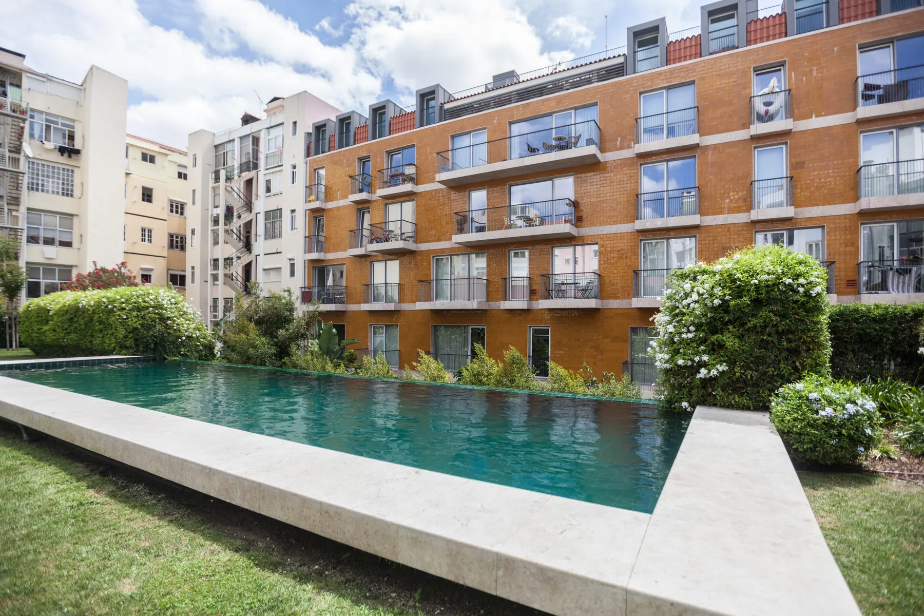 Una piscina al aire libre está frente a un edificio de apartamentos de ladrillo.