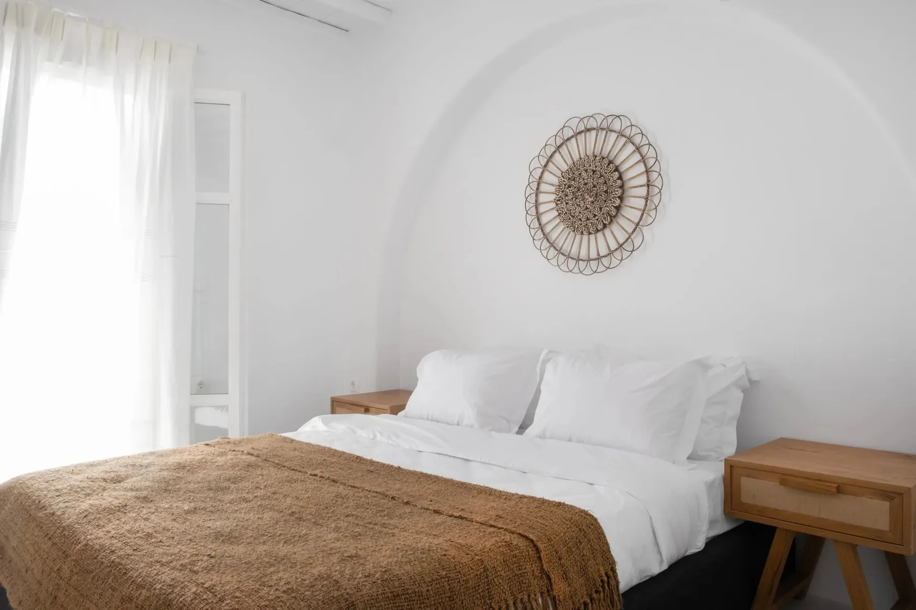 Un dormitorio con ropa de cama blanca y una manta marrón.
