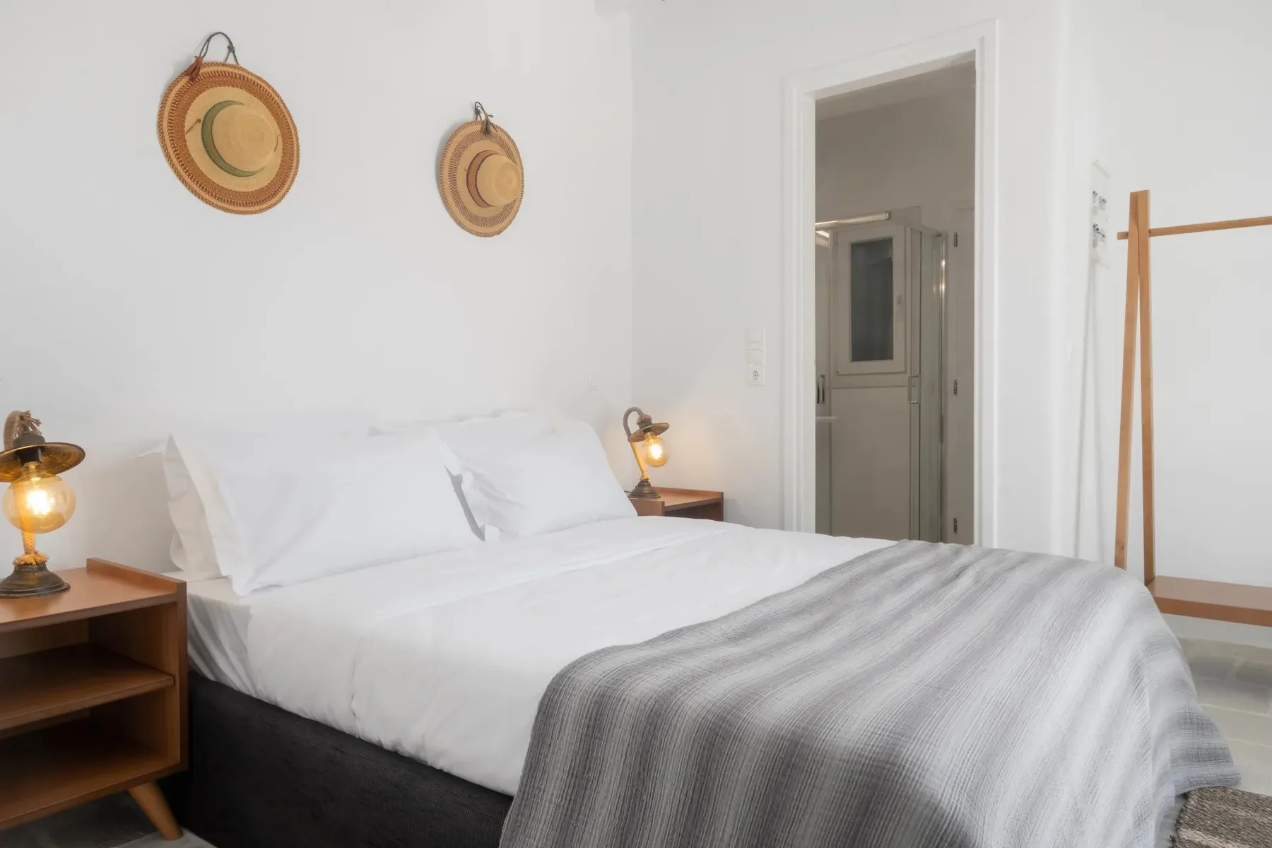 Un dormitorio con una cama bien tendida y una manta gris.