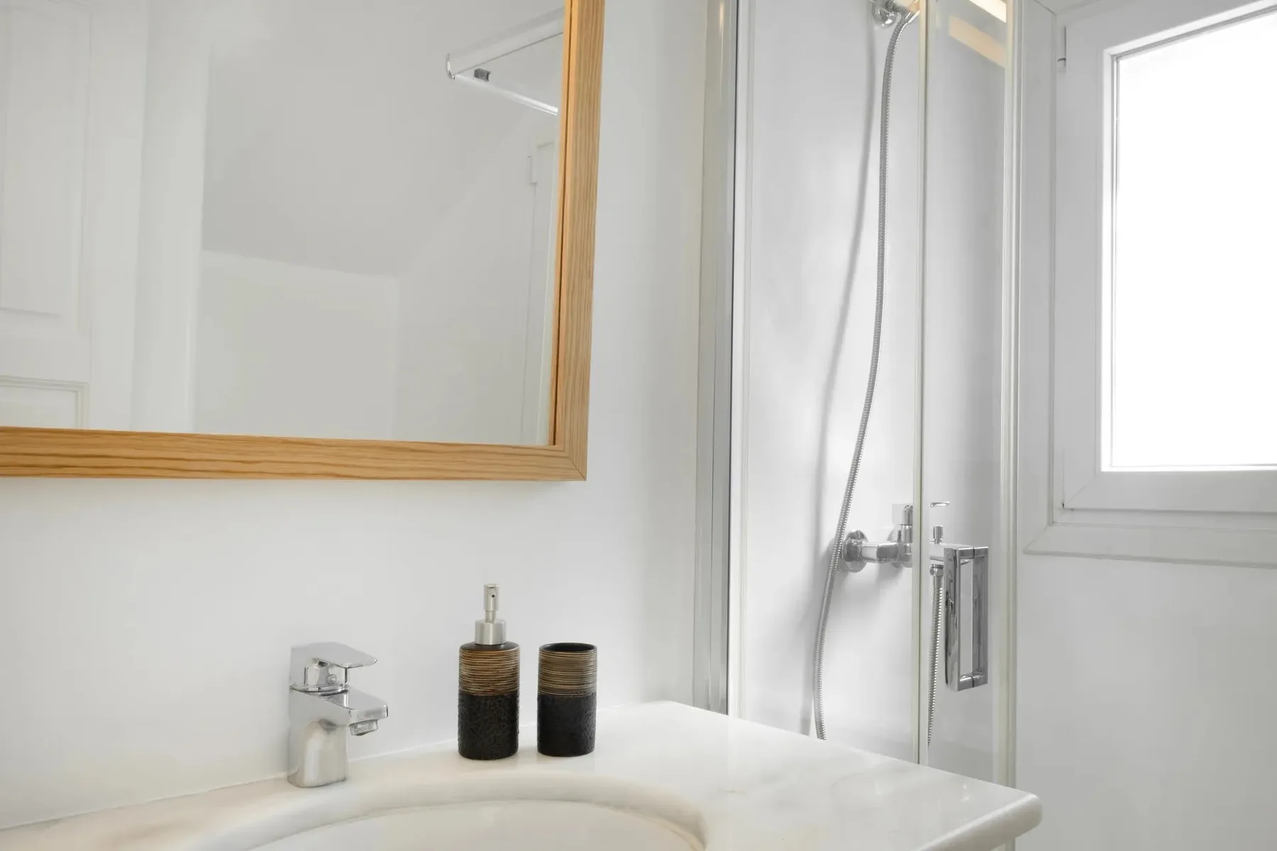 Un lavabo de baño luminoso con espejo y ducha.