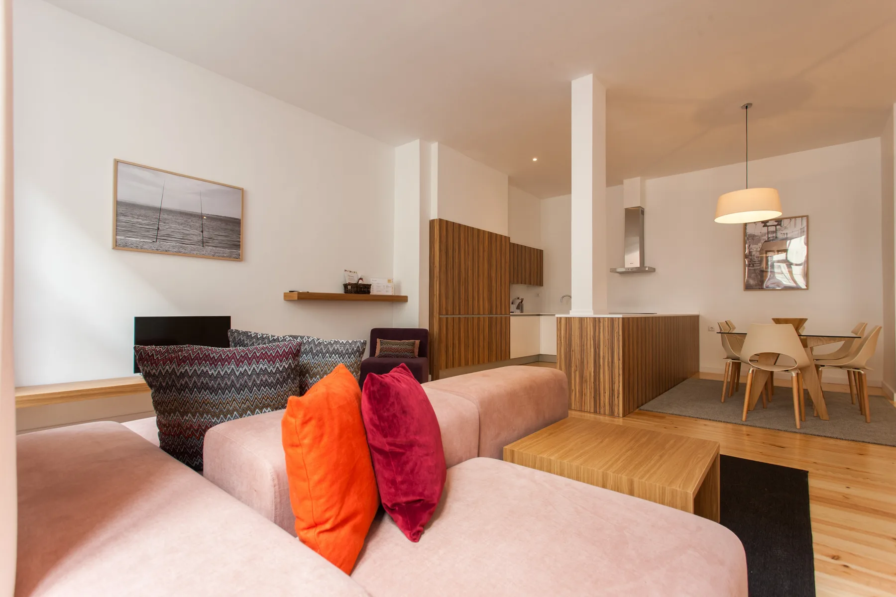 Sala de estar y comedor con asientos, una barra de madera y una mesa de comedor.