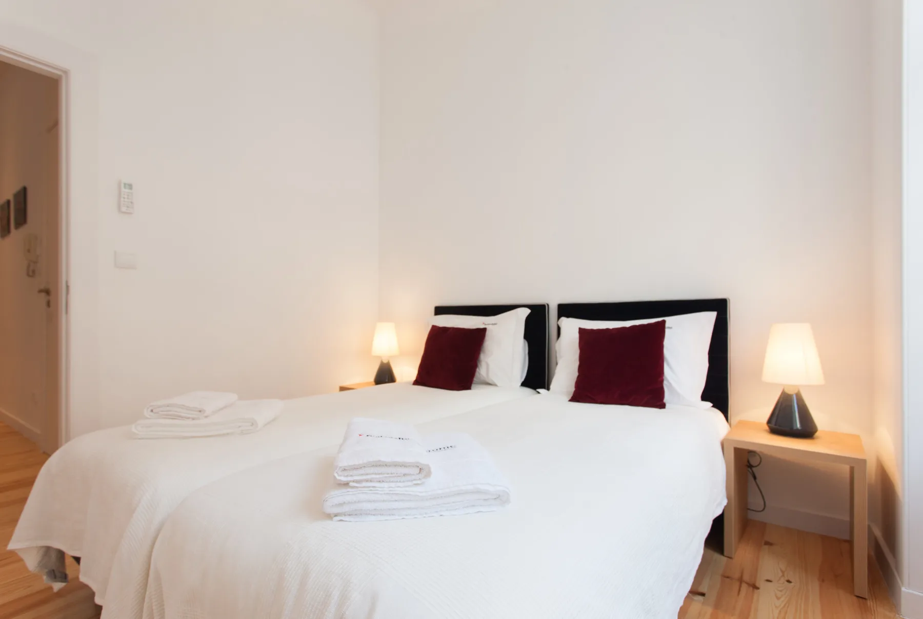 Un dormitorio luminoso con camas bien arregladas y lámparas de noche.