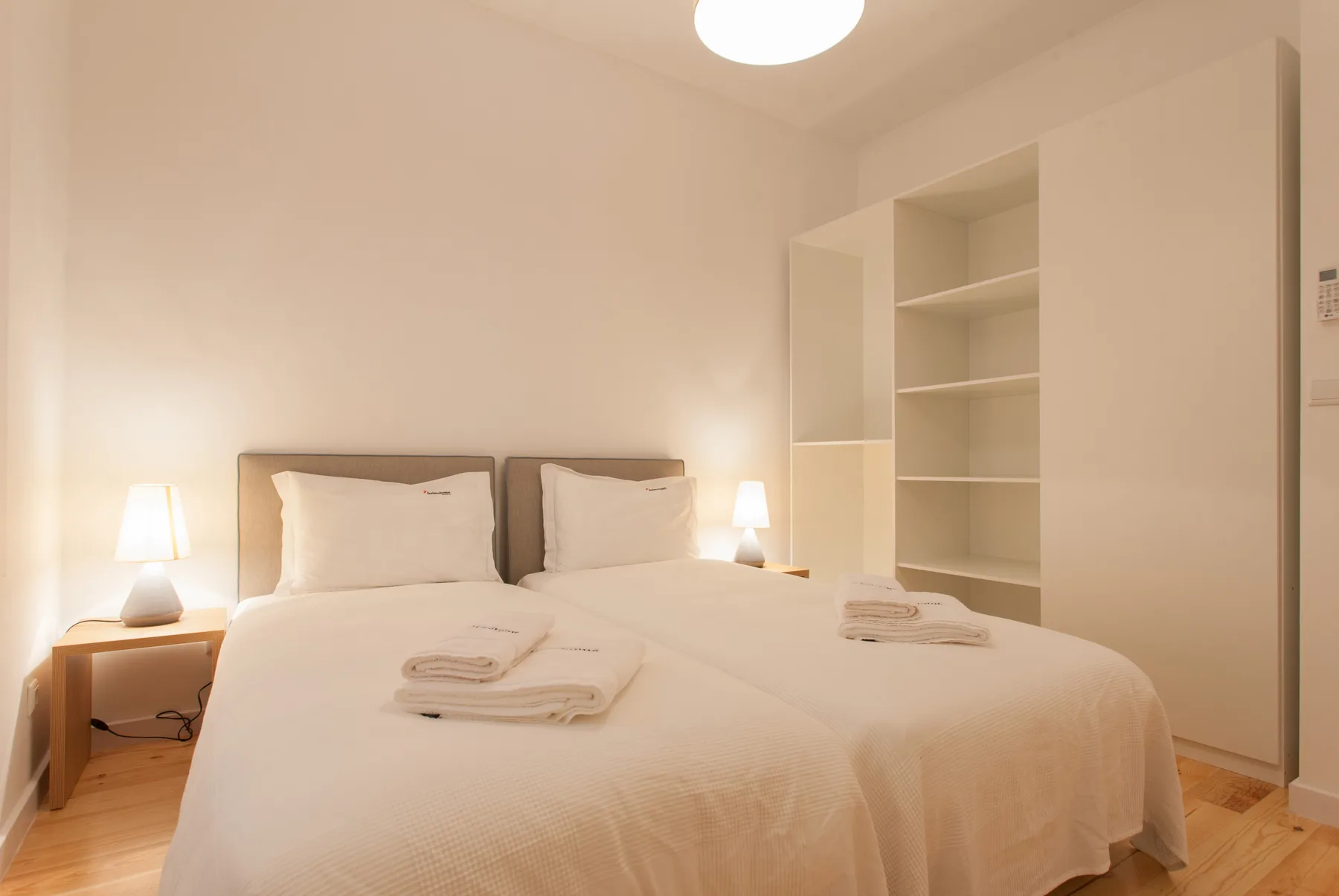 Un dormitorio con una cama doble, mesillas y estanterías abiertas.