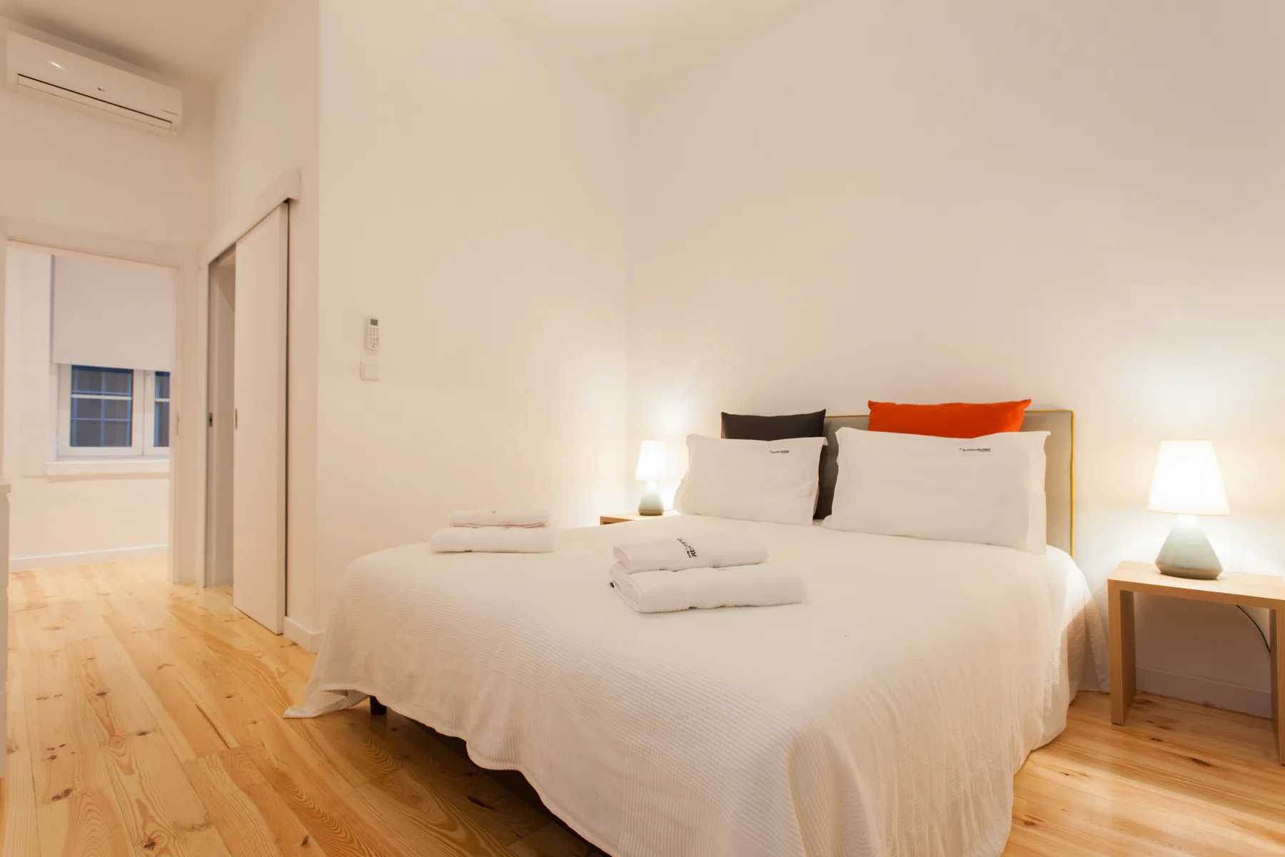 Un dormitorio luminoso con una cama bien tendida y lámparas de noche.