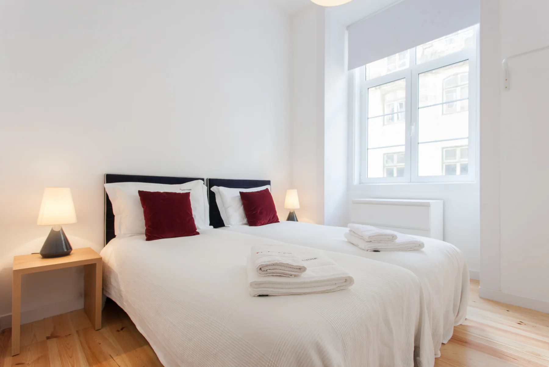 Un dormitorio luminoso con una cama, mesitas de noche y una ventana grande.