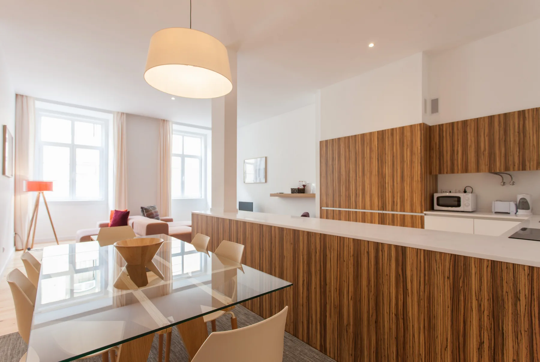Una sala-comedor de concepto abierto con barra de cocina y ventanas grandes.