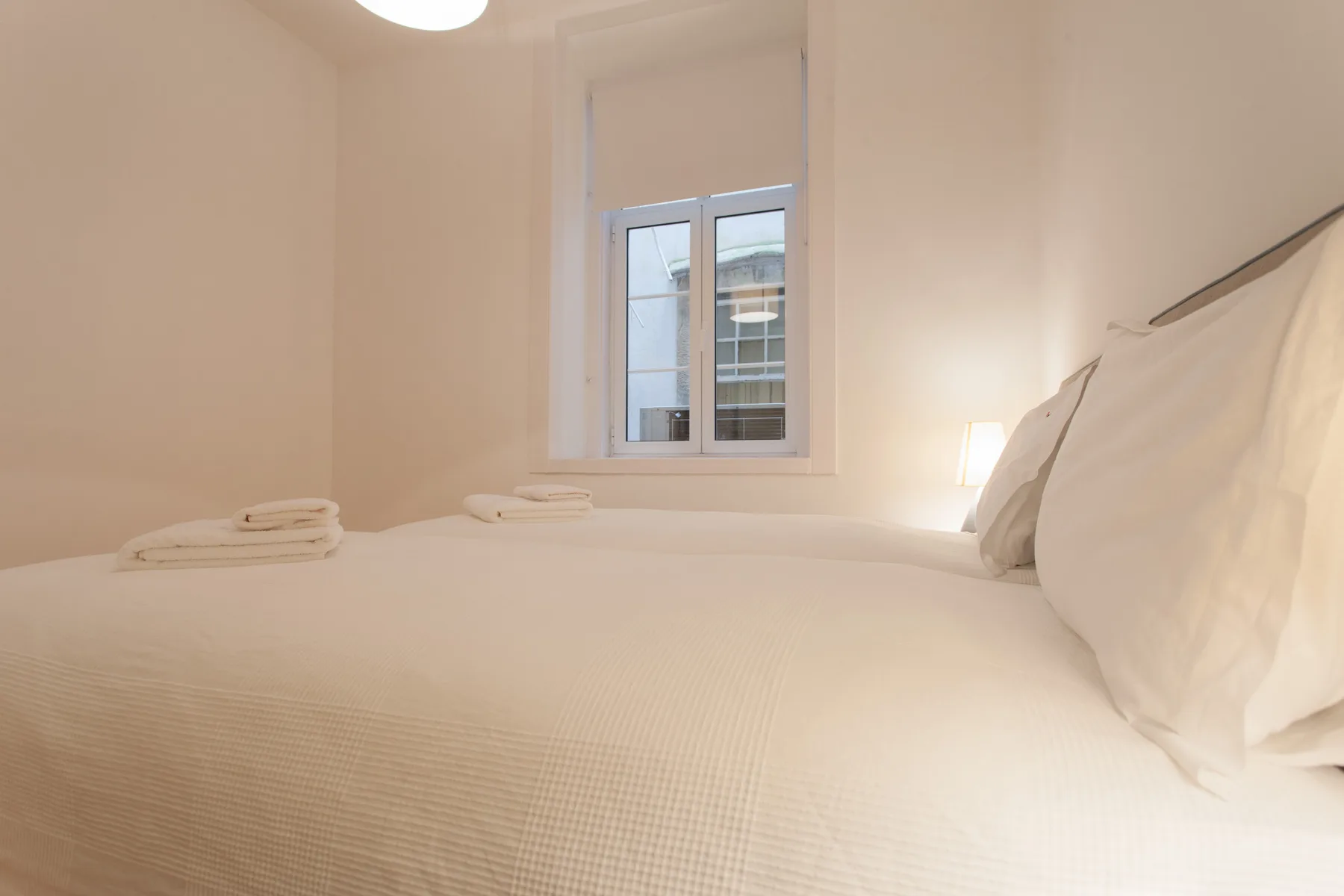 Un dormitorio con una cama bien hecha bajo una ventana.