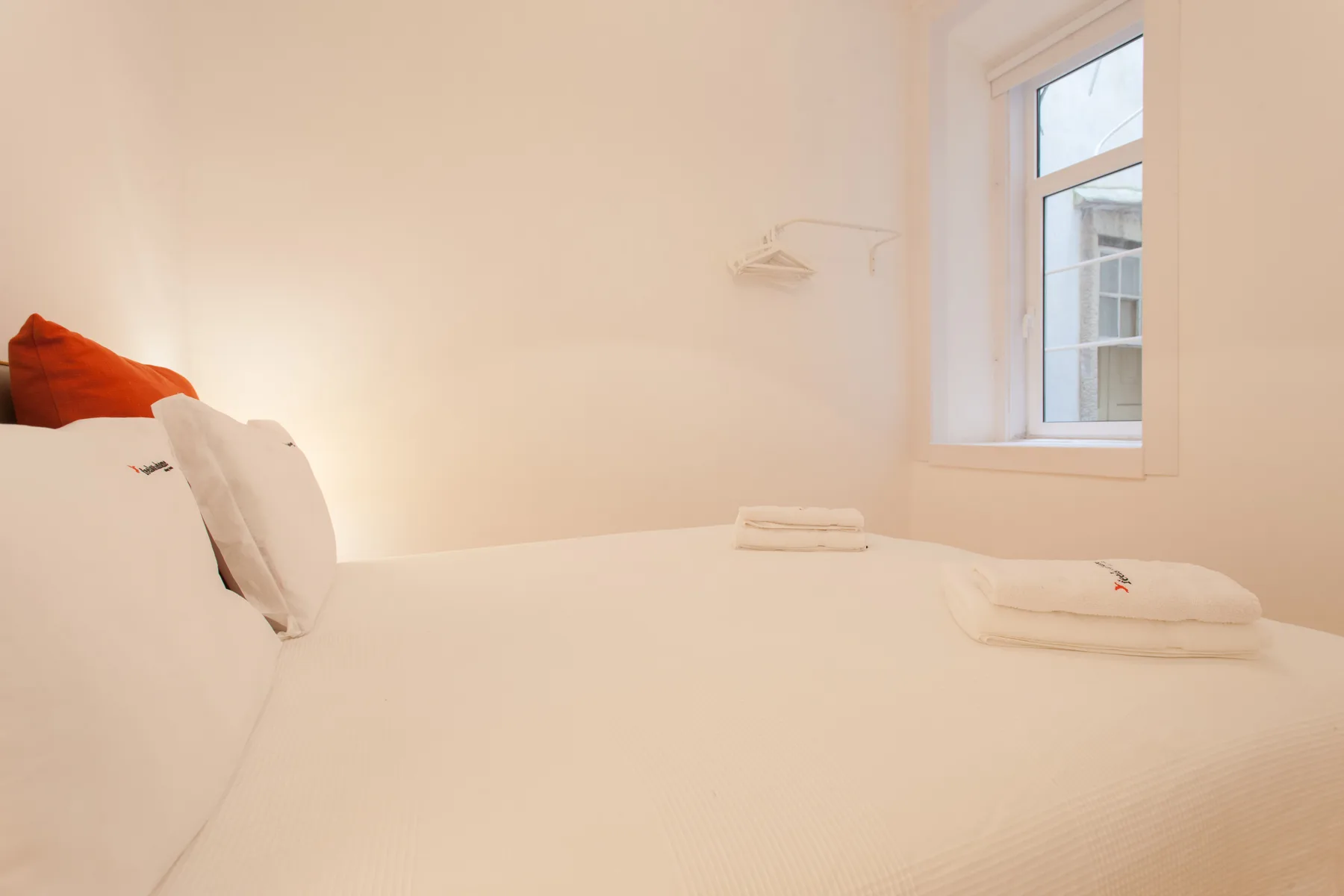 Un dormitorio con ropa de cama blanca y una ventana junto a la cama.