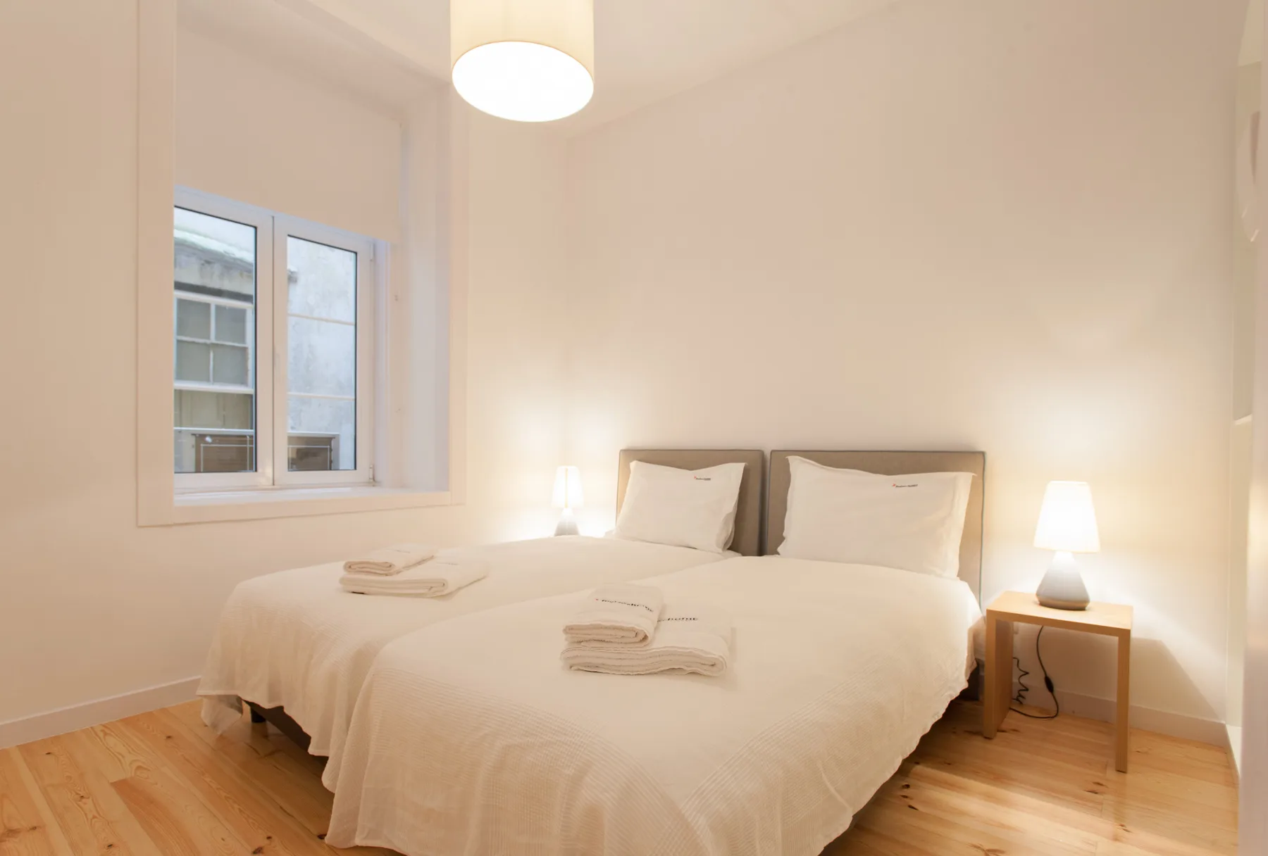 Un dormitorio luminoso con una cama, mesitas de noche y una ventana.