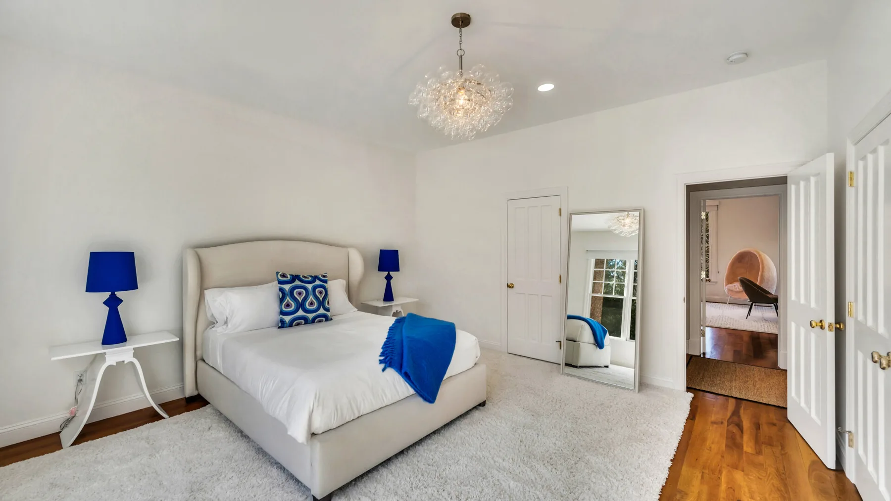 Un dormitorio luminoso con una cama bien tendida y detalles azules.