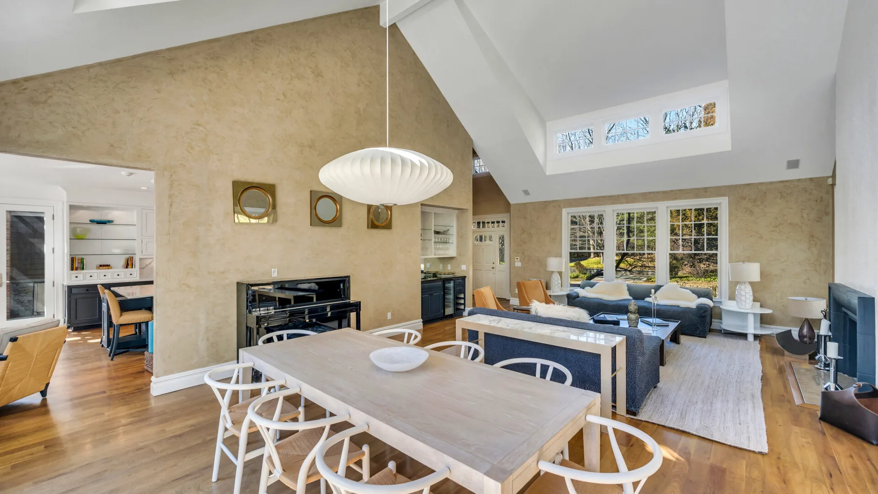Una luminosa zona diáfana de comedor y sala de estar con una mesa grande y asientos.