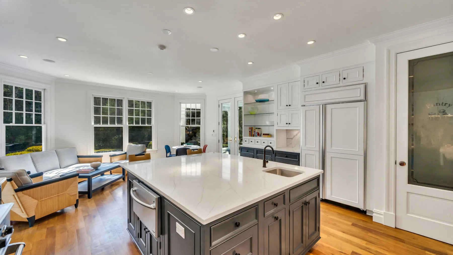 Una cocina luminosa con una isla grande y asientos junto a las ventanas.