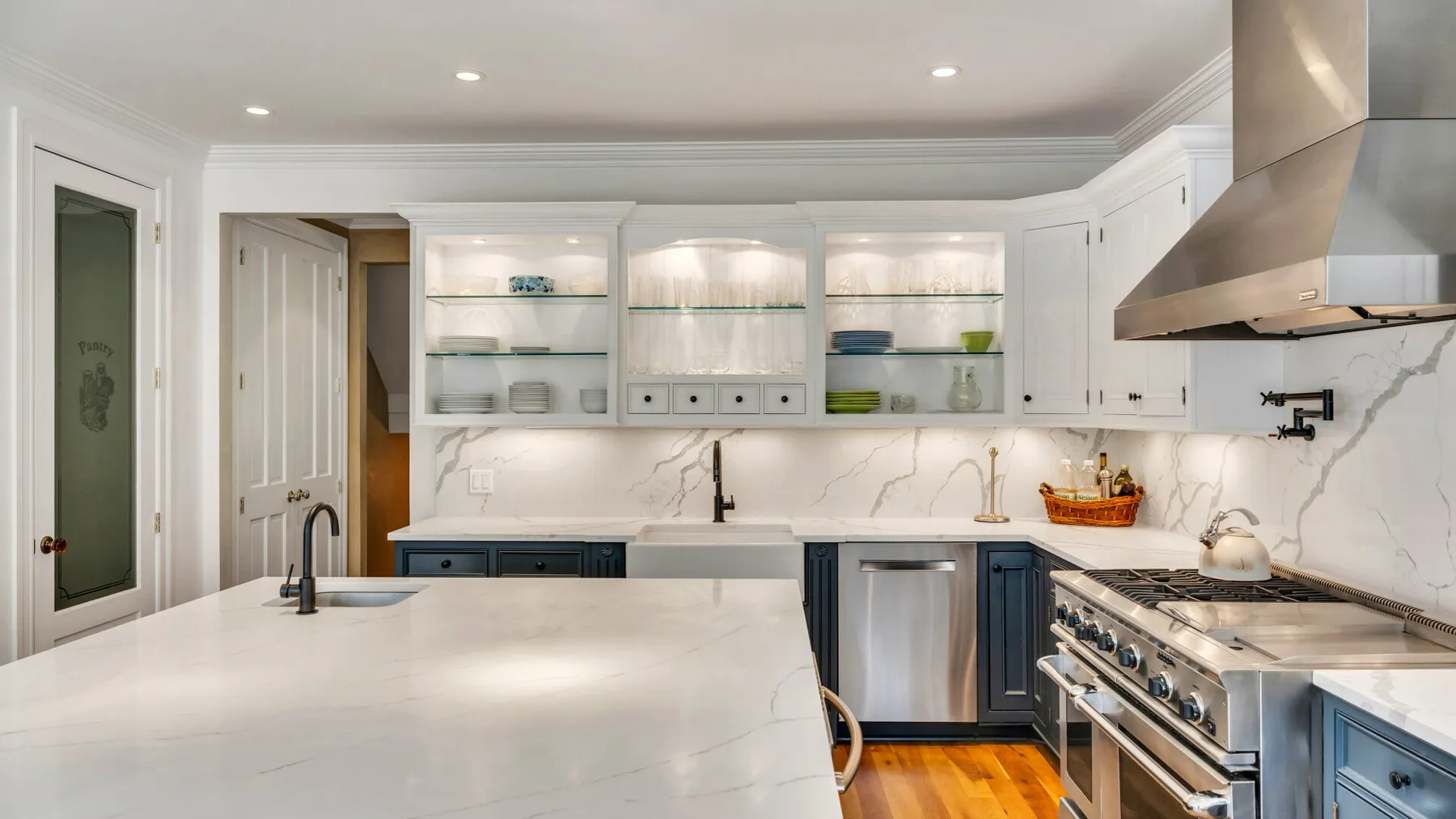 Una cocina luminosa con gabinetes blancos, una isla amplia y electrodomésticos de acero inoxidable.