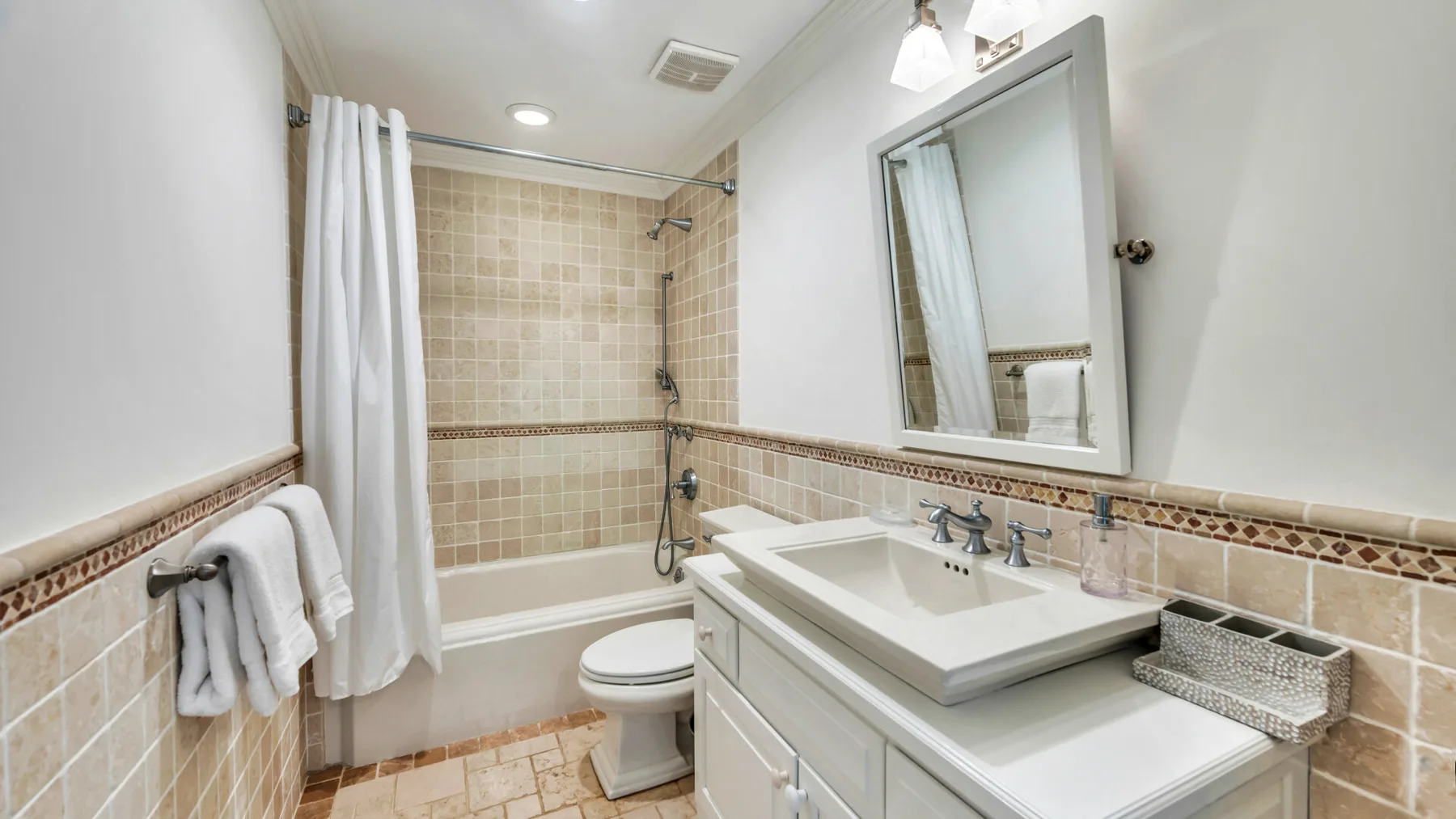 Un baño con azulejos, bañera, cortina de ducha y lavabo.