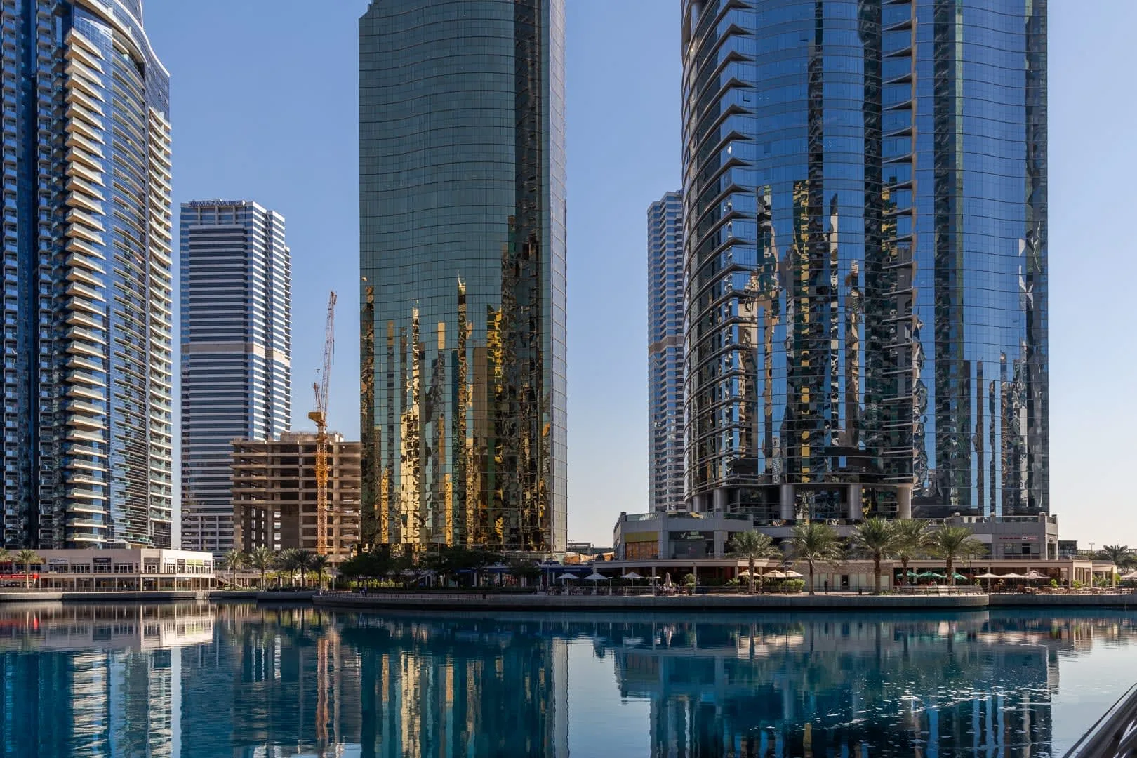 Altos edificios modernos junto al agua se reflejan en la superficie.