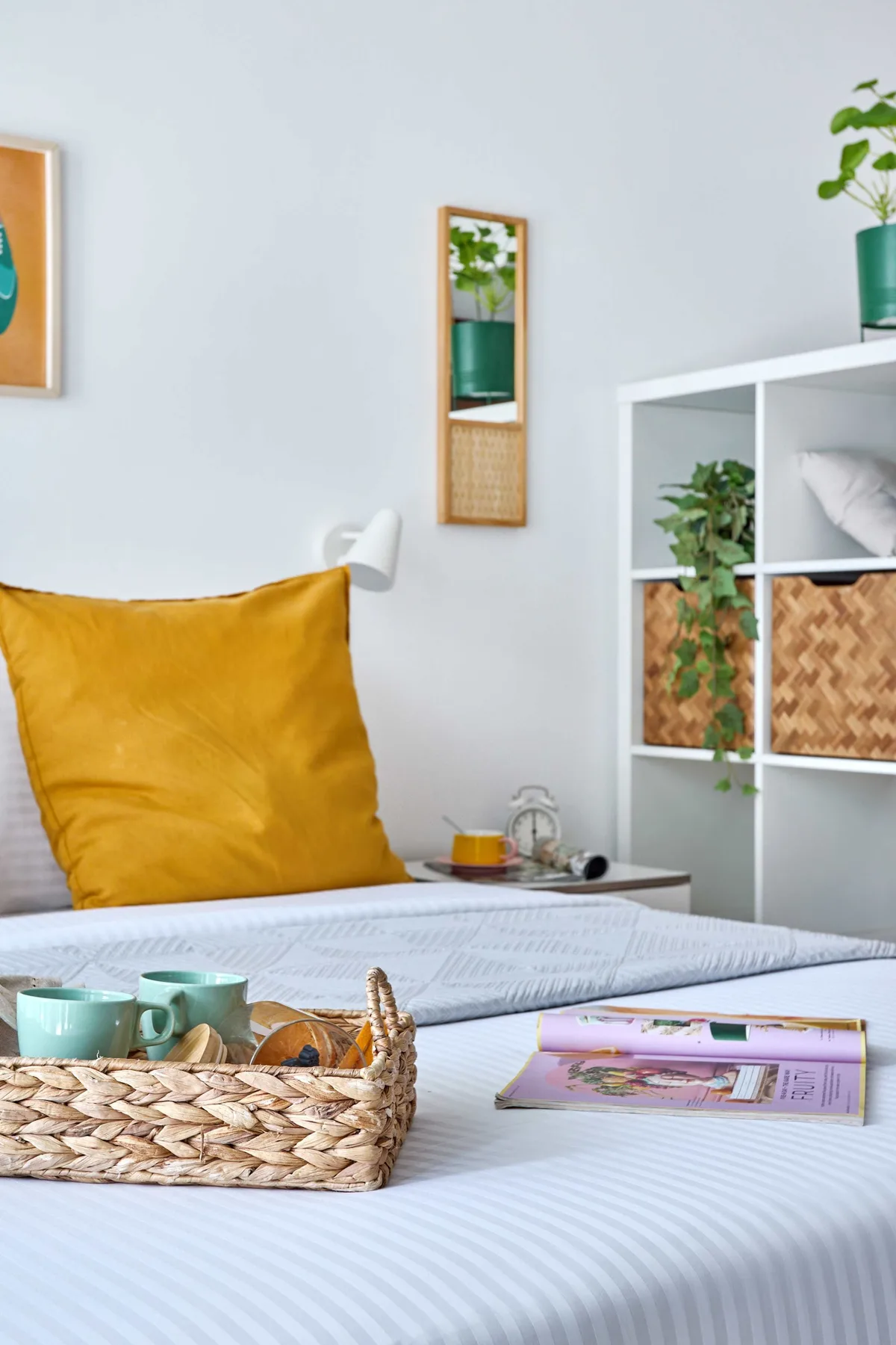 Un dormitorio con una cama, un cojín color mostaza y una cesta tejida.