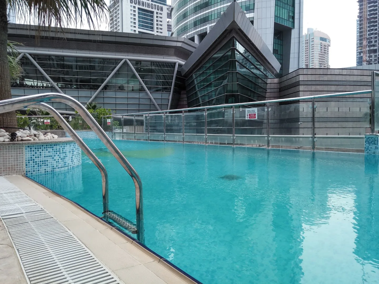 Una piscina al aire libre está junto a un edificio moderno de vidrio y acero.