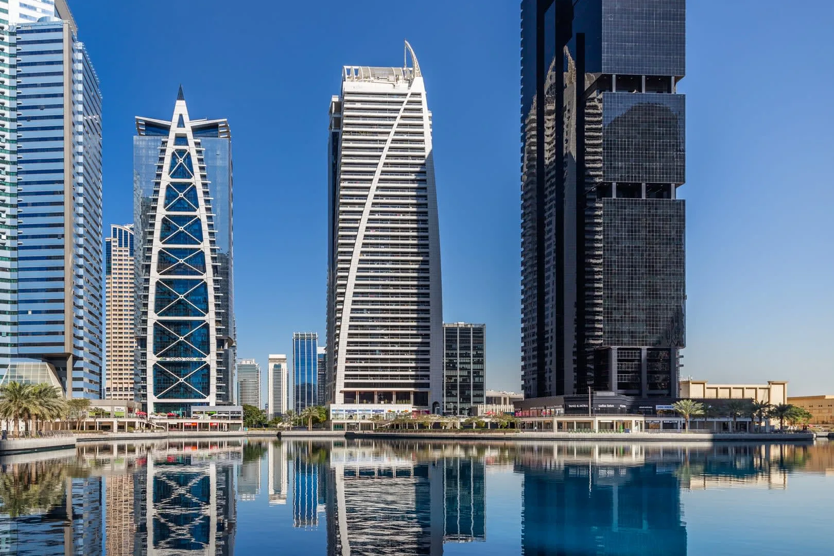 Un horizonte urbano de edificios altos modernos reflejados en aguas tranquilas.