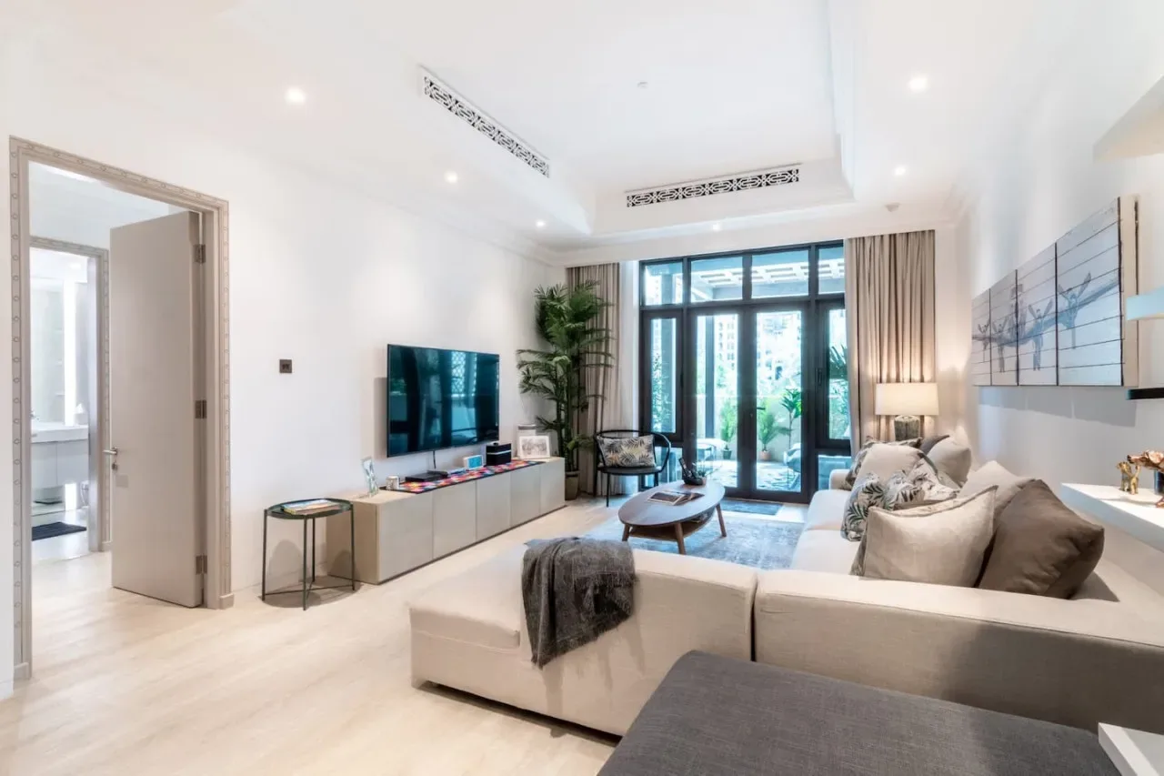 A bright living room with seating, a television, and large glass doors.
