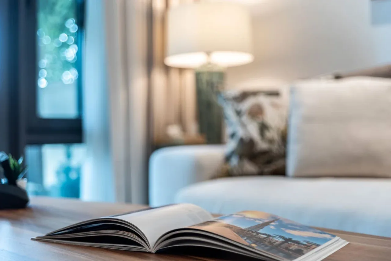 An open book rests on a table in front of a living room seating area.