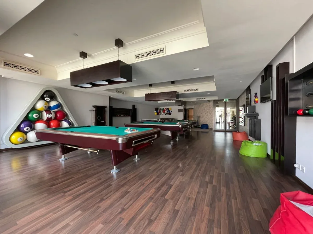 A recreation room with pool tables and a rack of billiard balls.