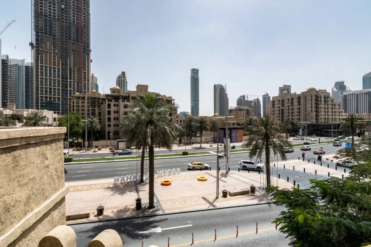 An urban streetscape with palm trees, roads, and high-rise buildings.