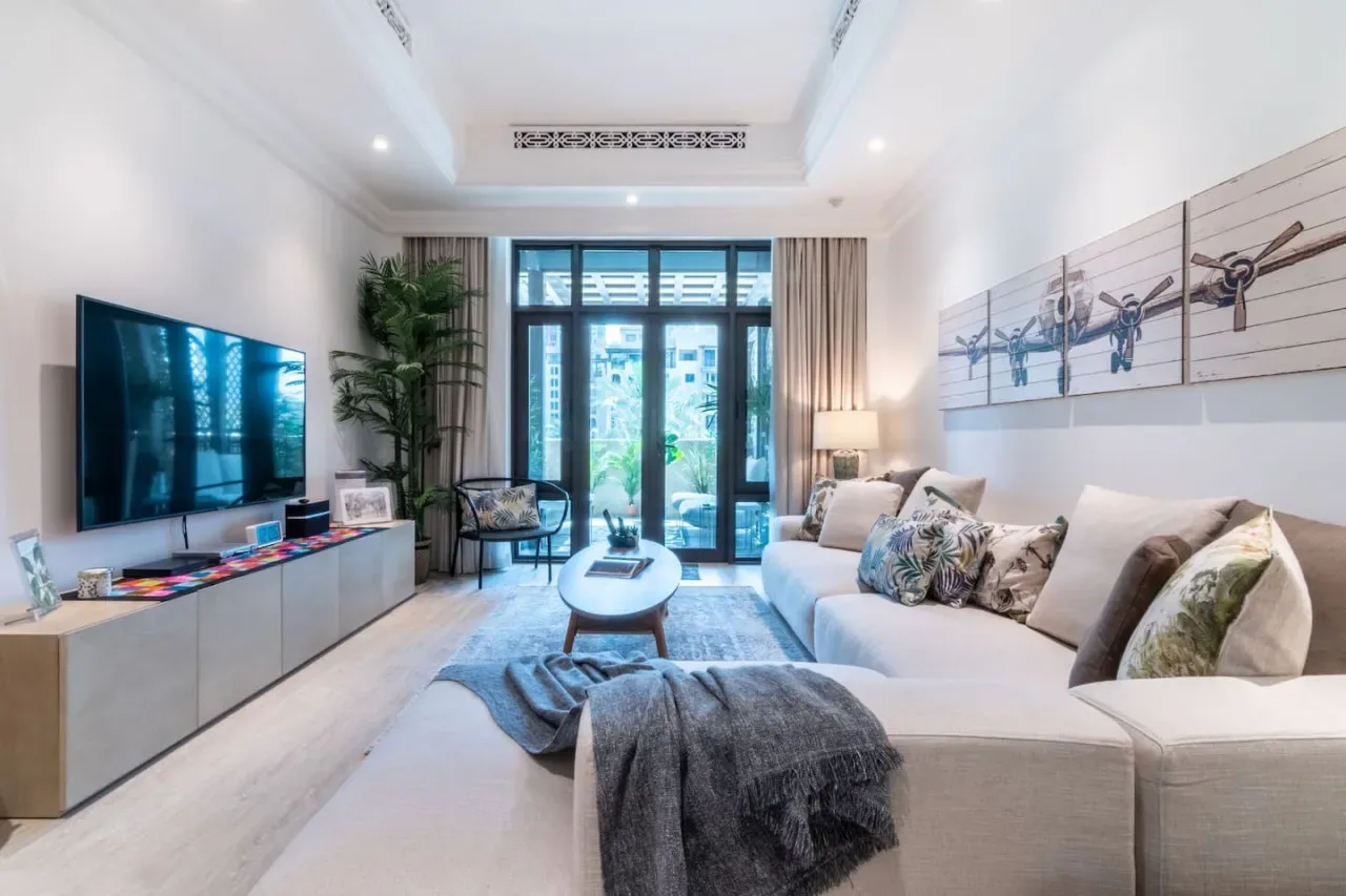 A bright living room with a large seating area and floor-to-ceiling windows.