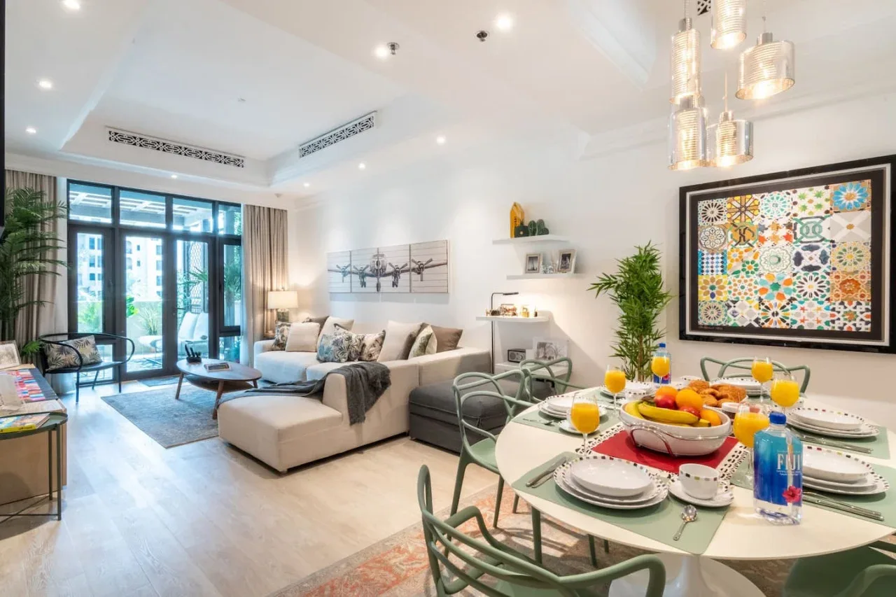 A bright living and dining room with a sofa, set table, and large glass doors.