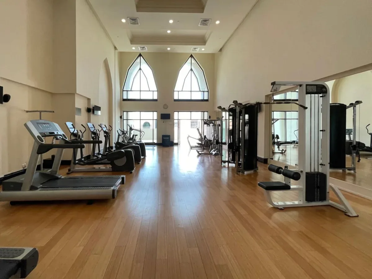 A fitness room with exercise machines arranged along a wood-floored space.