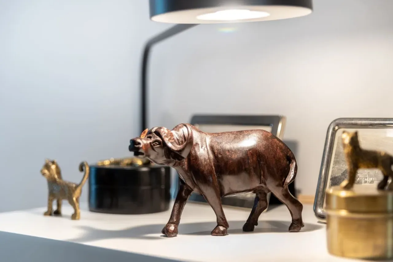 A shelf displays a bronze-colored animal figurine beside small decorative objects.